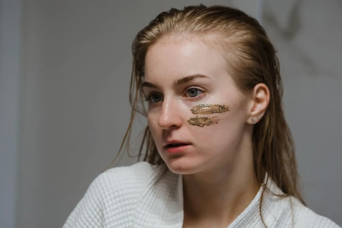 Дівчина в халаті зі смужками скрабу на щоках